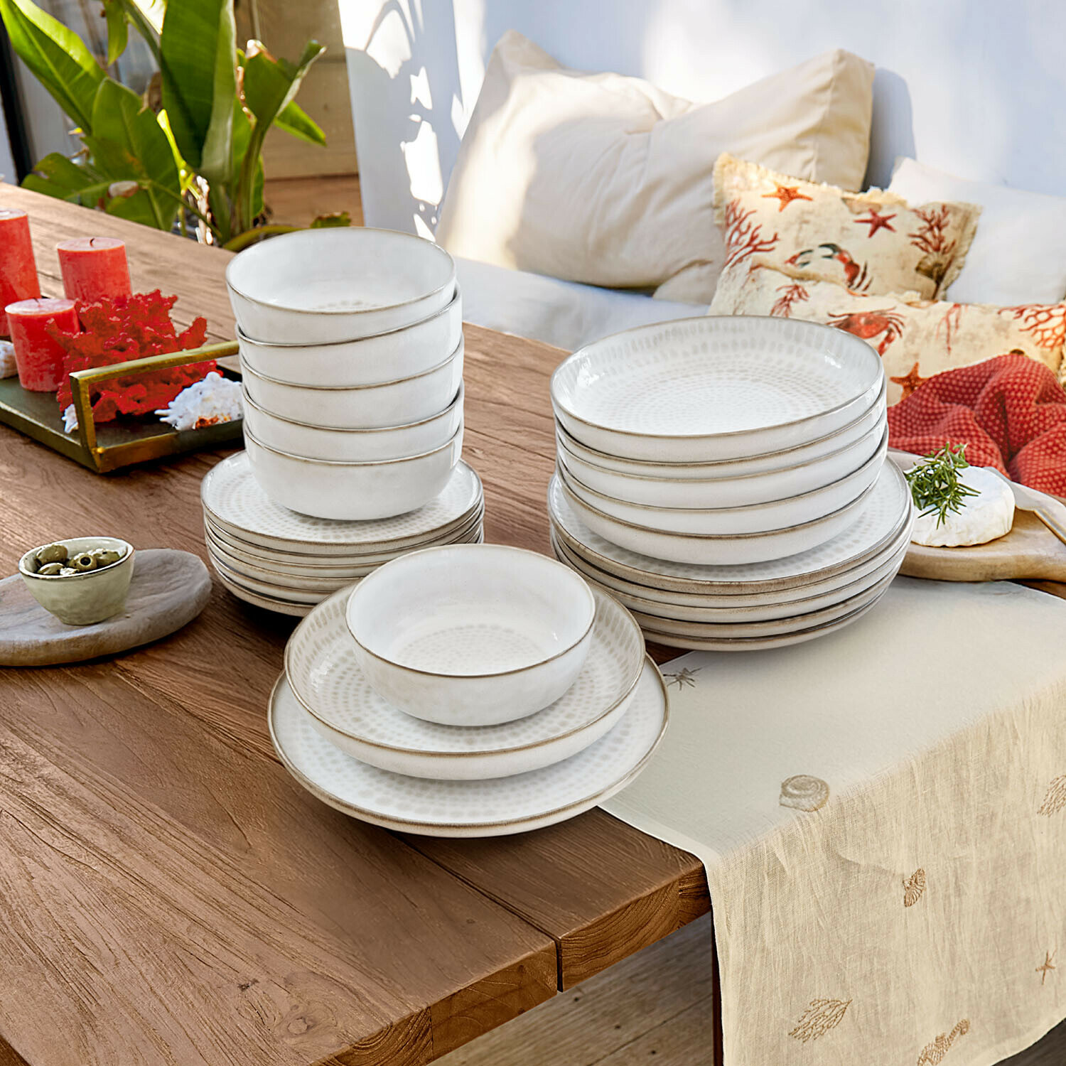 Weißes Keramik-Geschirrset mit Tellern und Schalen auf Holztisch mit Dekoration