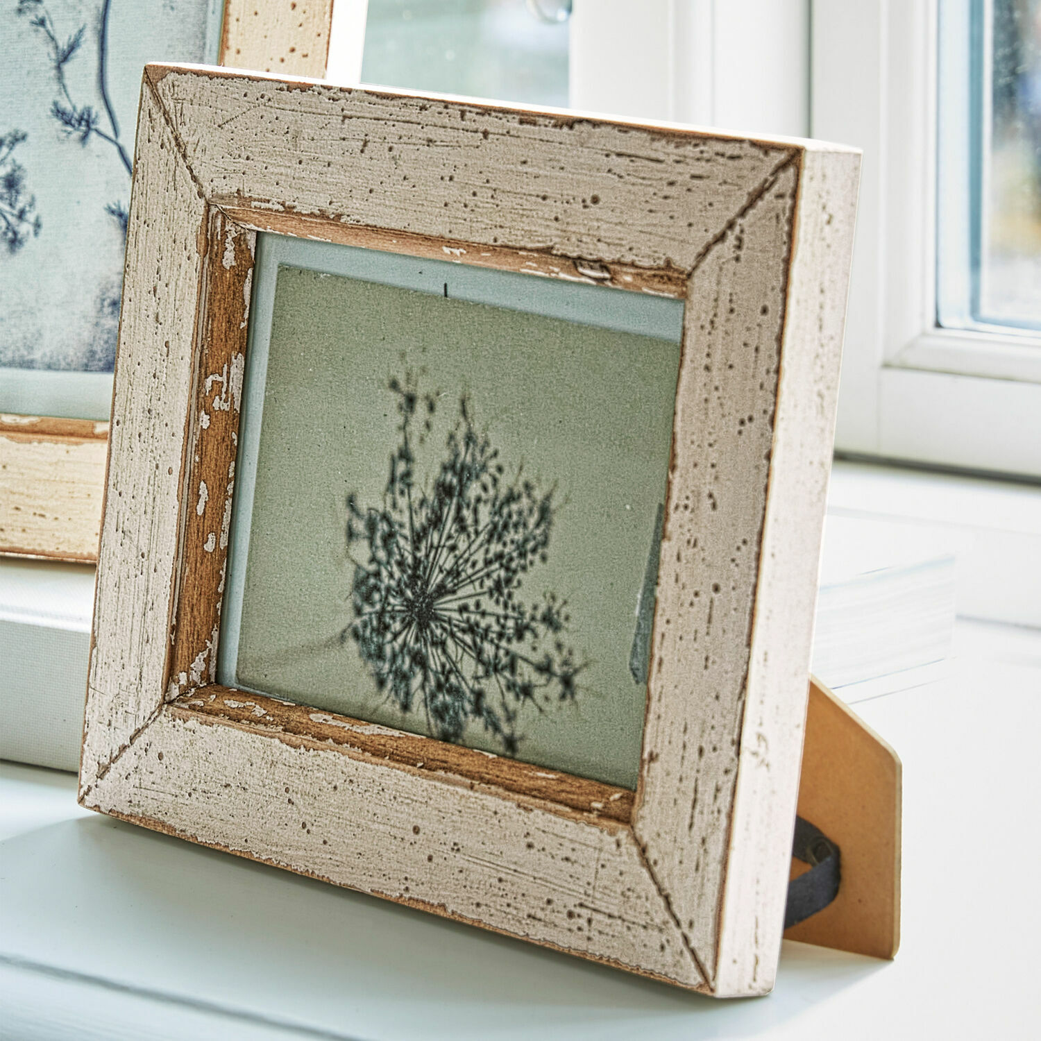 Rustikaler Bilderrahmen aus Holz in weißem Used-Look auf Schreibtisch am Fenster