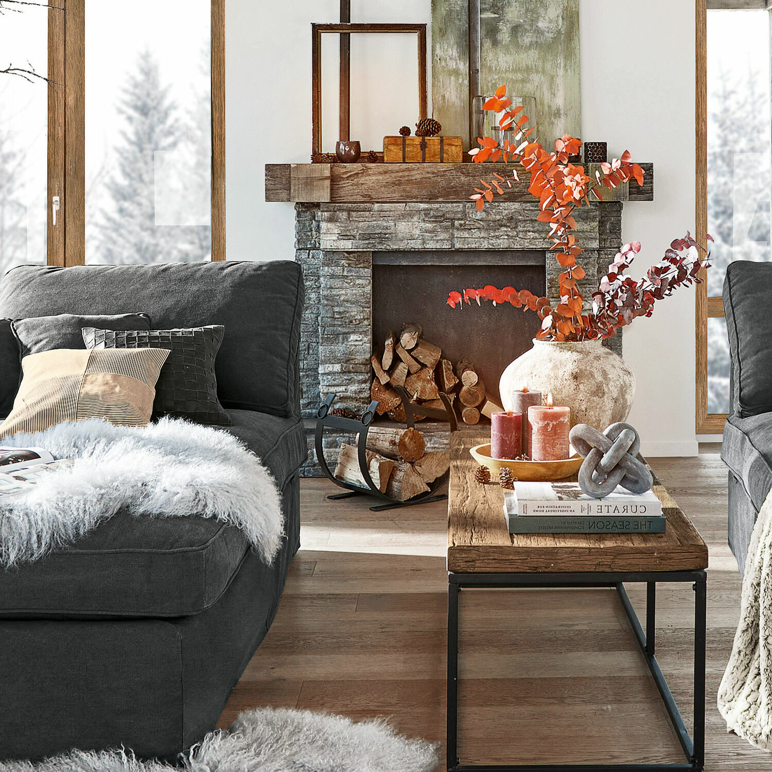 Gemütliches Wohnzimmer mit grauem Sofa, Holztisch und steinernem Kamin mit herbstlicher Dekoration