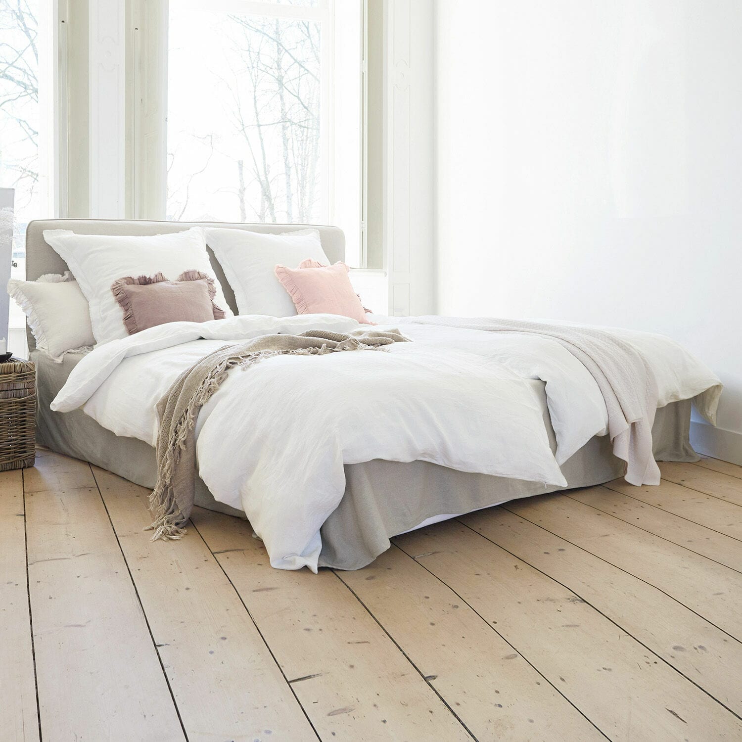 Bett Aubrianne Hellgraues Polsterbett mit weißer Bettwäsche und pastellfarbenen Kissen in hellem Schlafzimmer