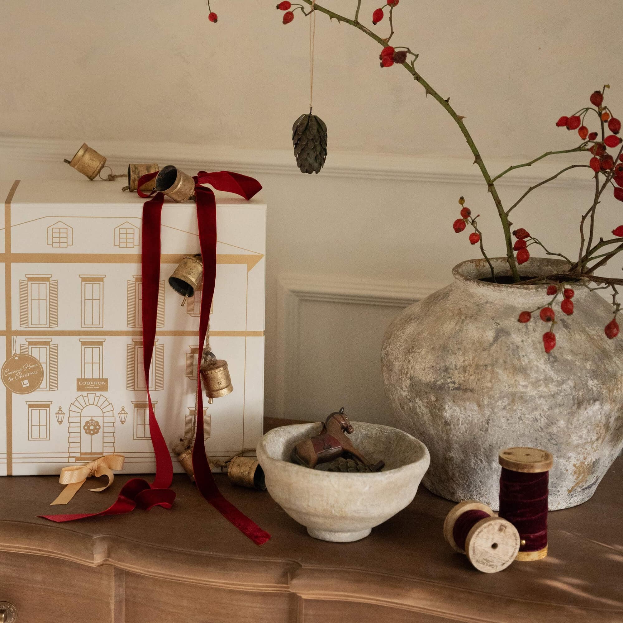 Weihnachtliche Dekoration mit roten Bändern, Keramikschale und großem Vase mit roten Beeren