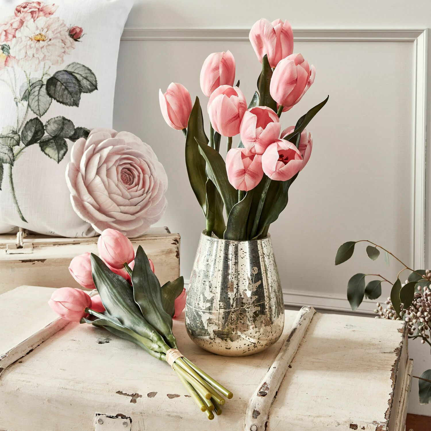Strauß rosa Tulpen mit grünen Blättern in silberner Vase auf weißem Holztisch