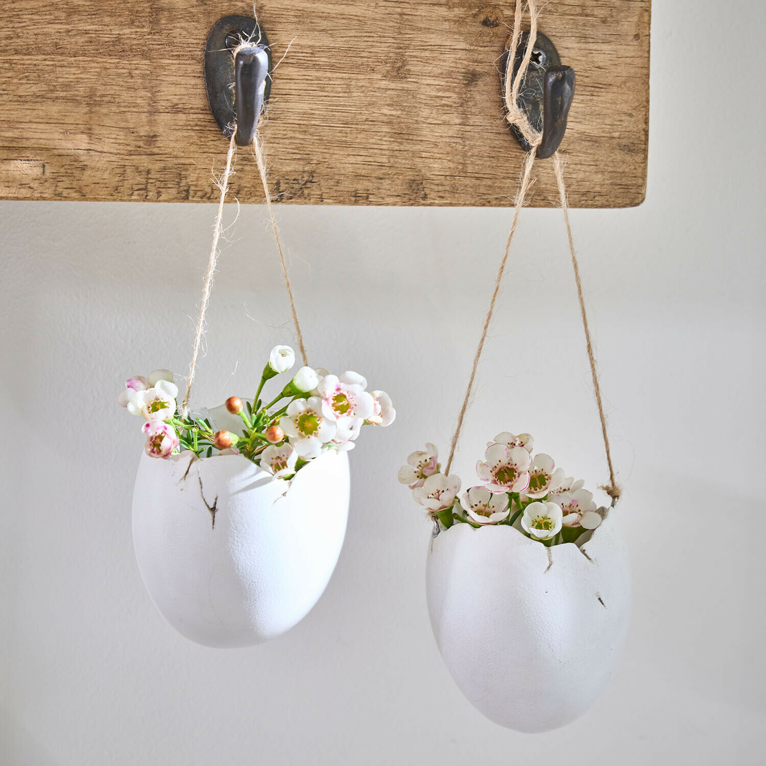 Hängevase 2er Set Nalena Zwei weiße Keramikblumentöpfe in Ei-Form mit Blumen, hängend an einem Holzbrett mit Haken