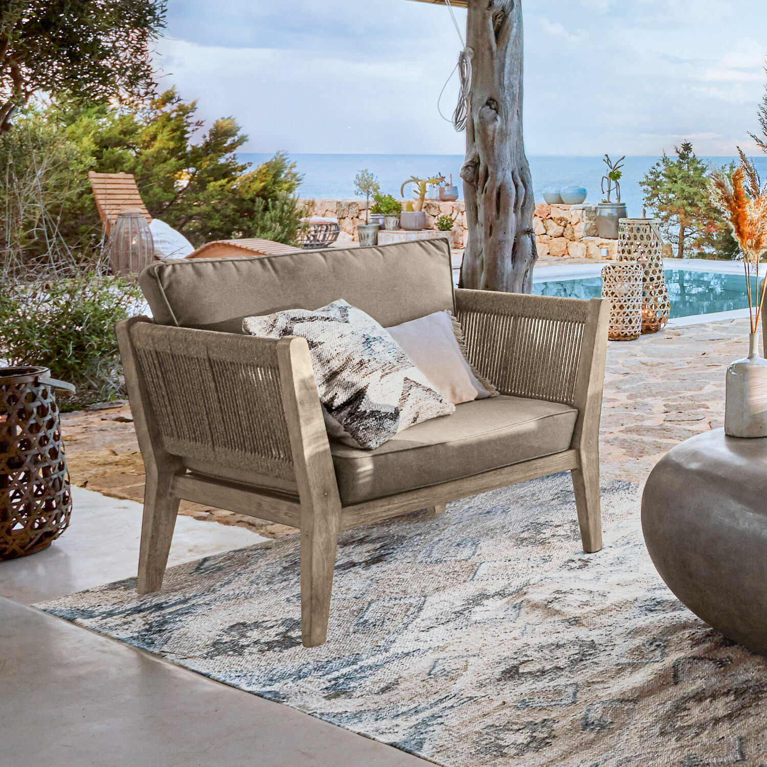 Sessel FSC®-100% Biarritz Outdoor-Sofa aus Holz und beigem Stoff auf Terrasse mit Meerblick