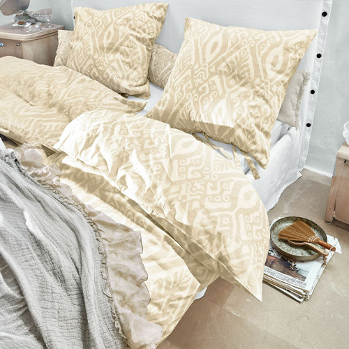Beige Bettwäsche mit geometrischem Muster aus weichem Stoff auf Bett in hellem Zimmer