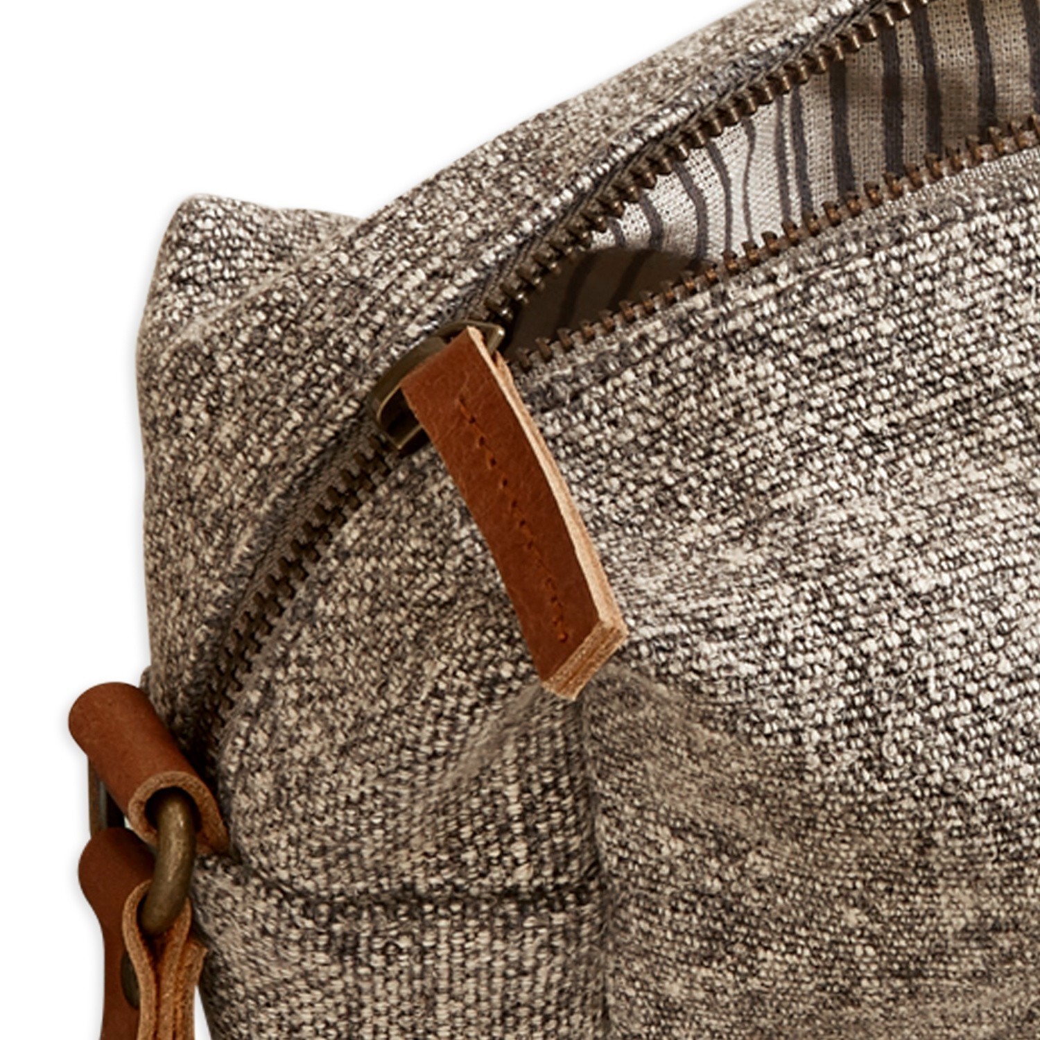 Nahaufnahme einer grau-braunen Stofftasche mit braunem Lederreißverschluss und Riemen