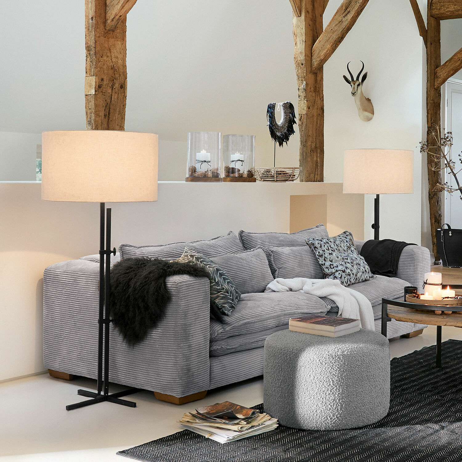 Graues Sofa aus weichem Stoff im Wohnzimmer mit Stehlampen und Dekorationen an Holzbalken