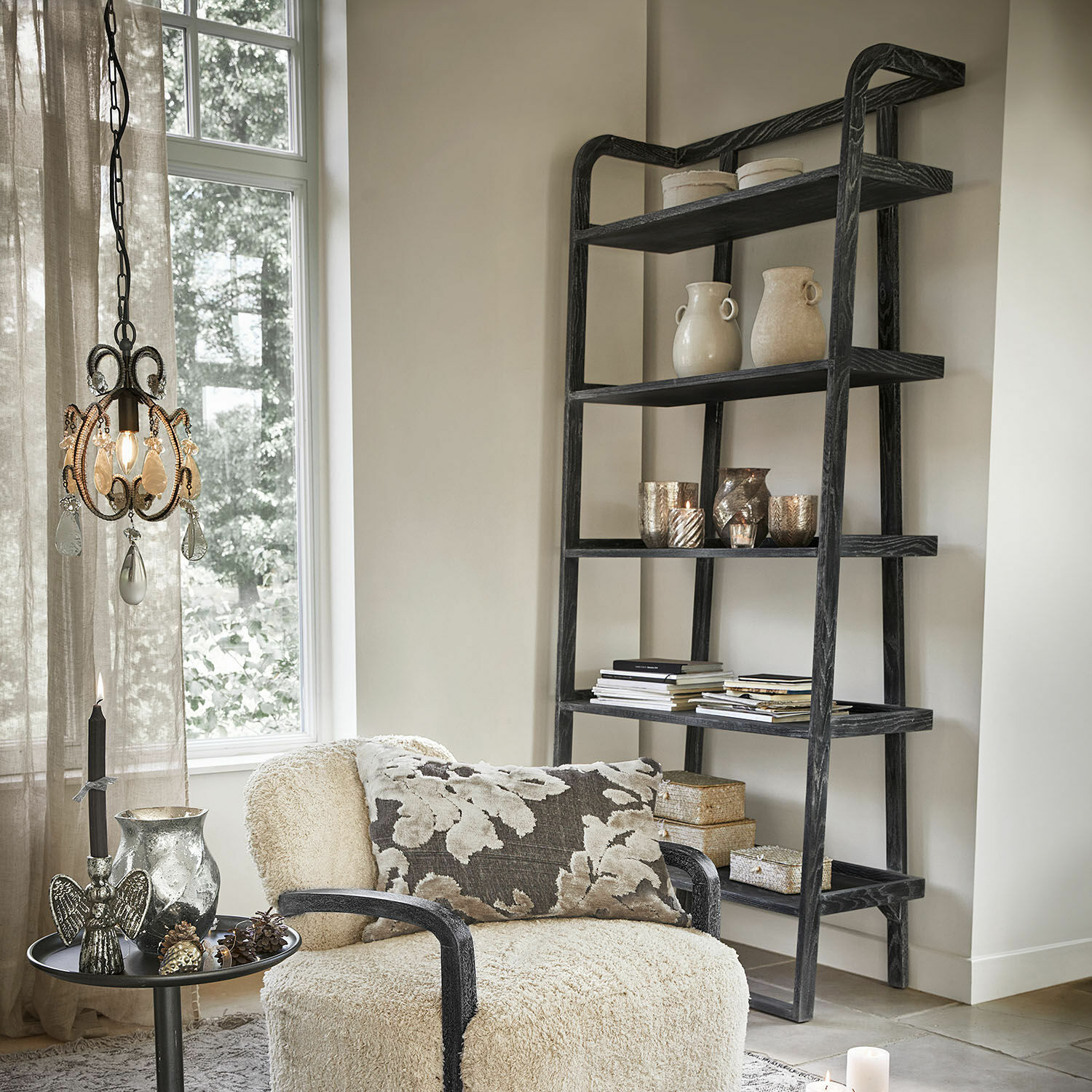 Schwarzes Holzregal im Leiterstil mit Dekorationen und Büchern in hellem Wohnzimmer