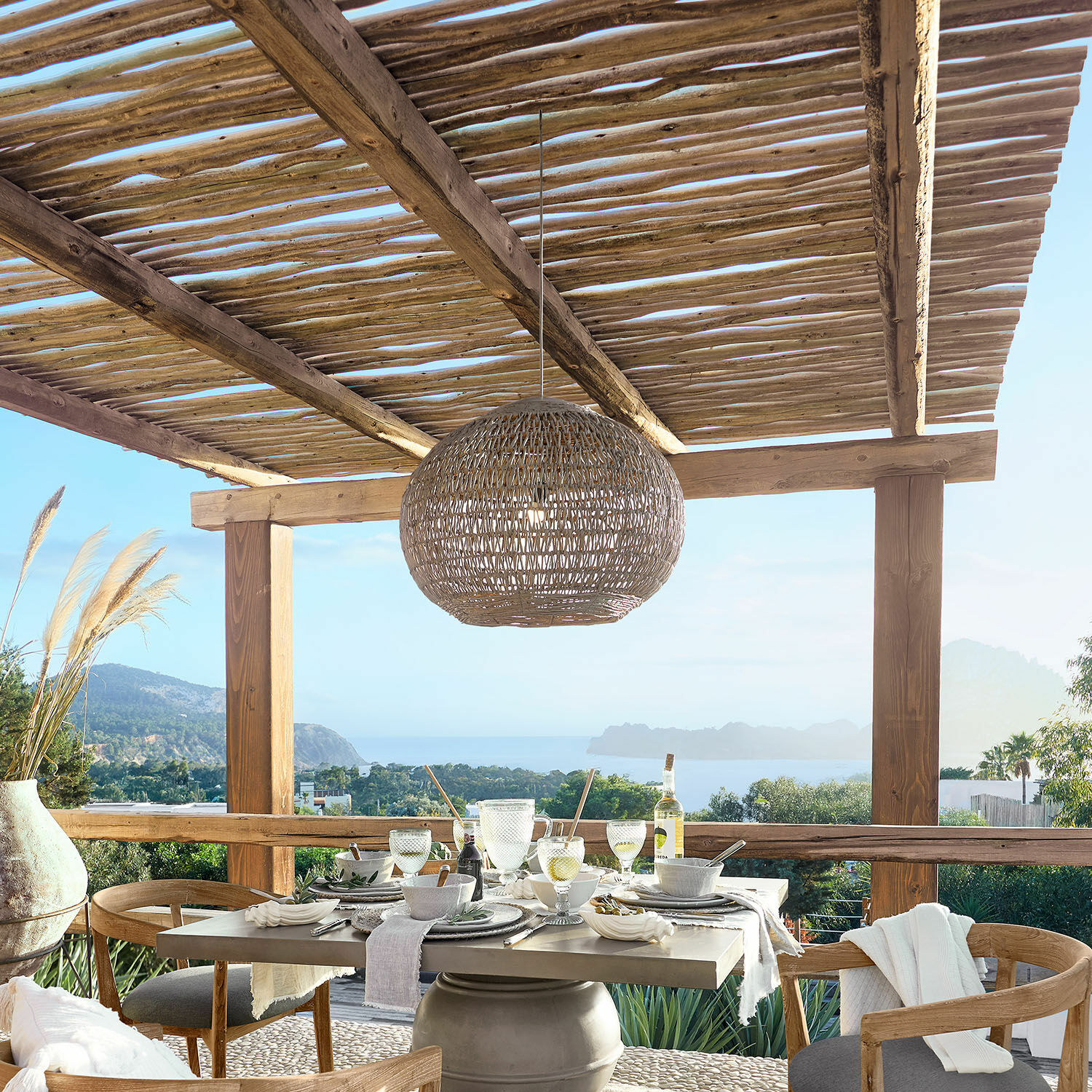 Terrassen-Essbereich mit Holztisch und Korbhängelampe, Meer- und Grünblick