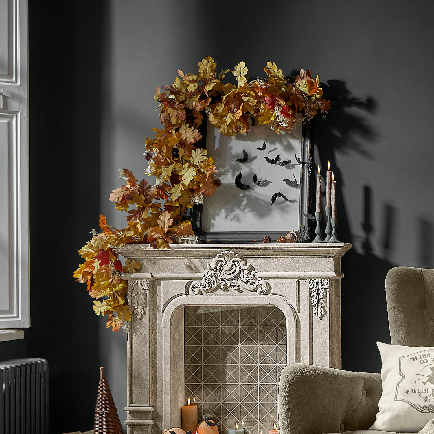 Dekorativer Kamin aus hellem Stein mit herbstlichem Blätterkranz und Kerzen im Wohnzimmer