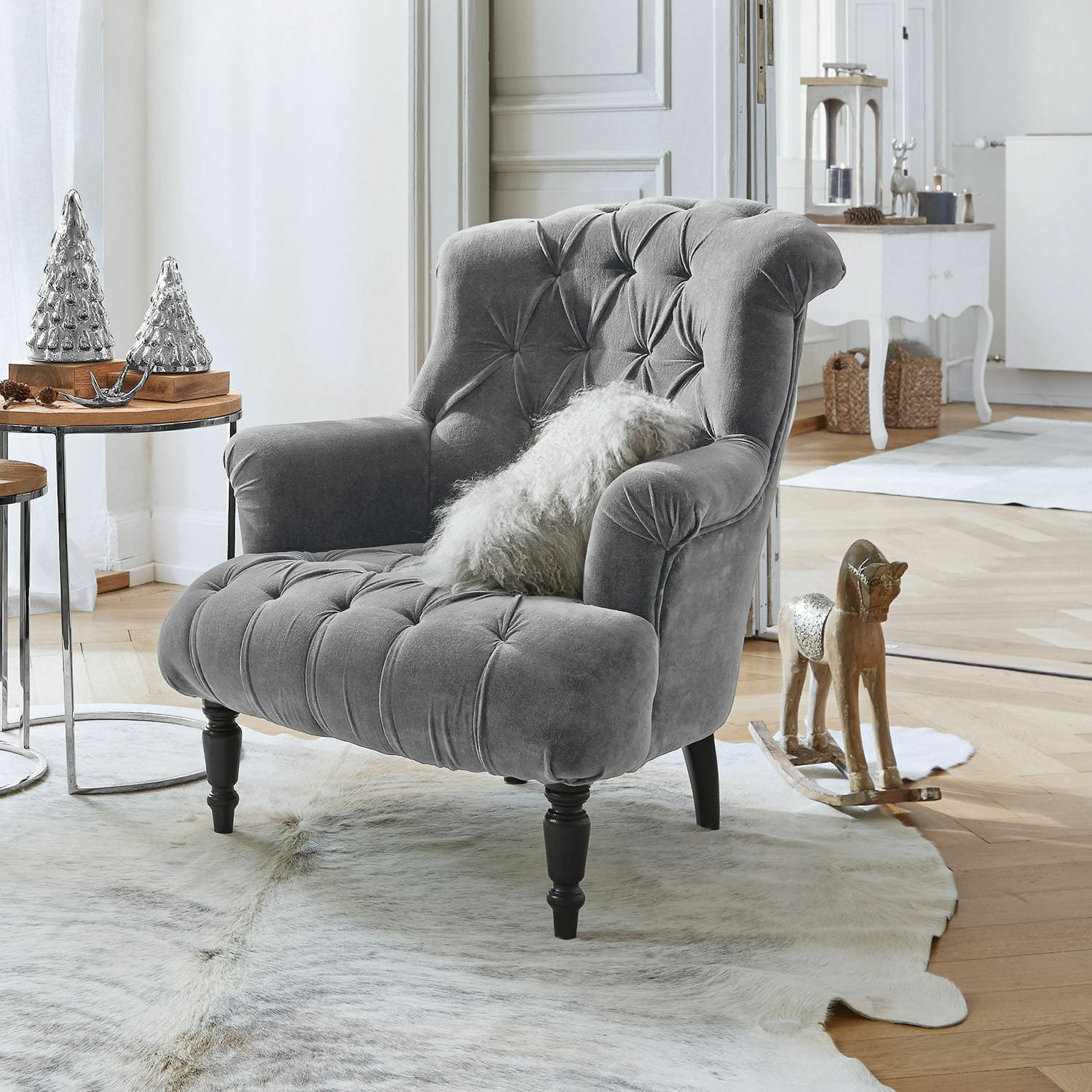 Sessel Parranquet Grau gepolsterter Samtfotel mit Knopfheftung und schwarzen Holzbeinen in hellem Wohnzimmer mit Dekoration