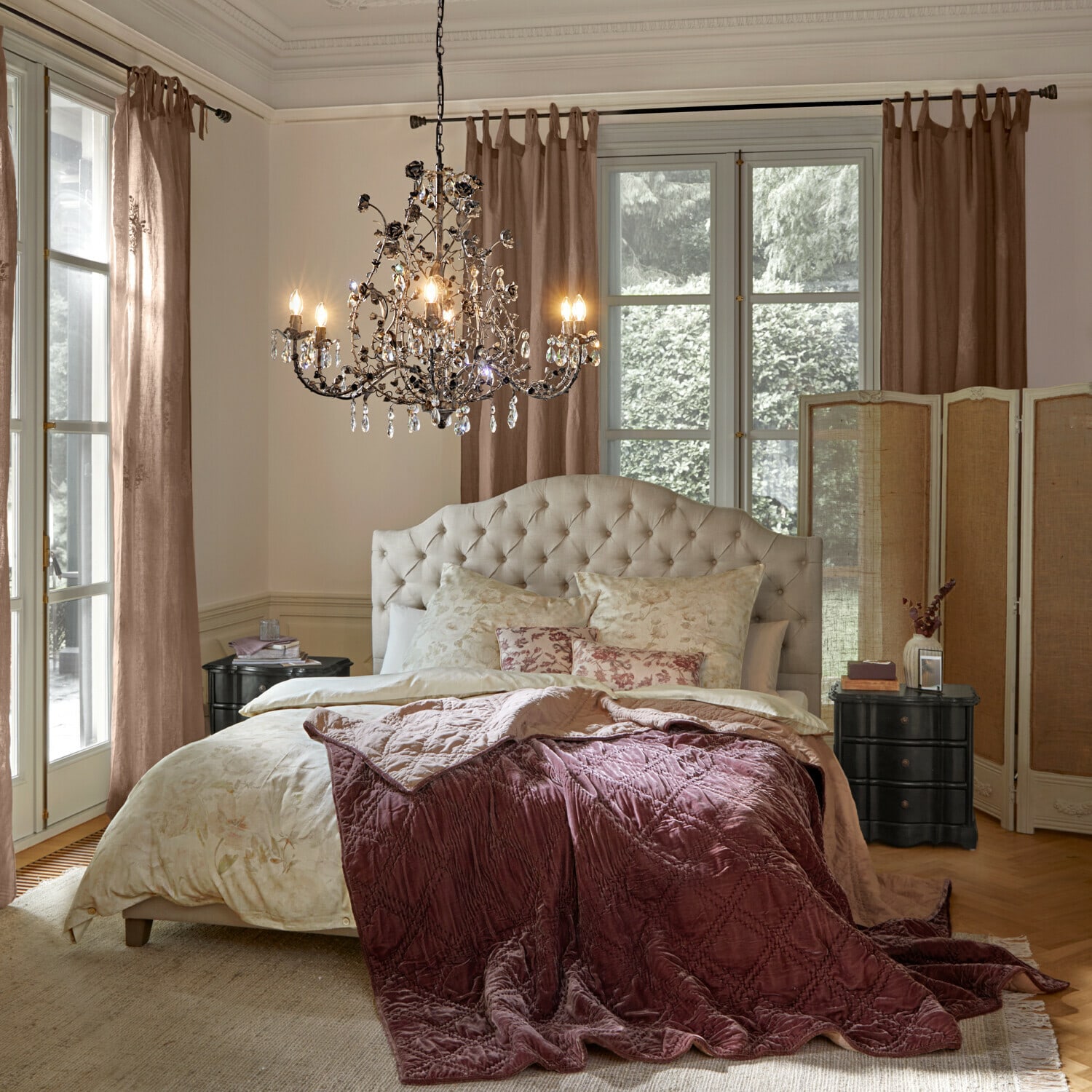 Gemütliches Schlafzimmer mit beige gepolstertem Kopfteil und bordeauxroter Samtdecke auf dem Bett