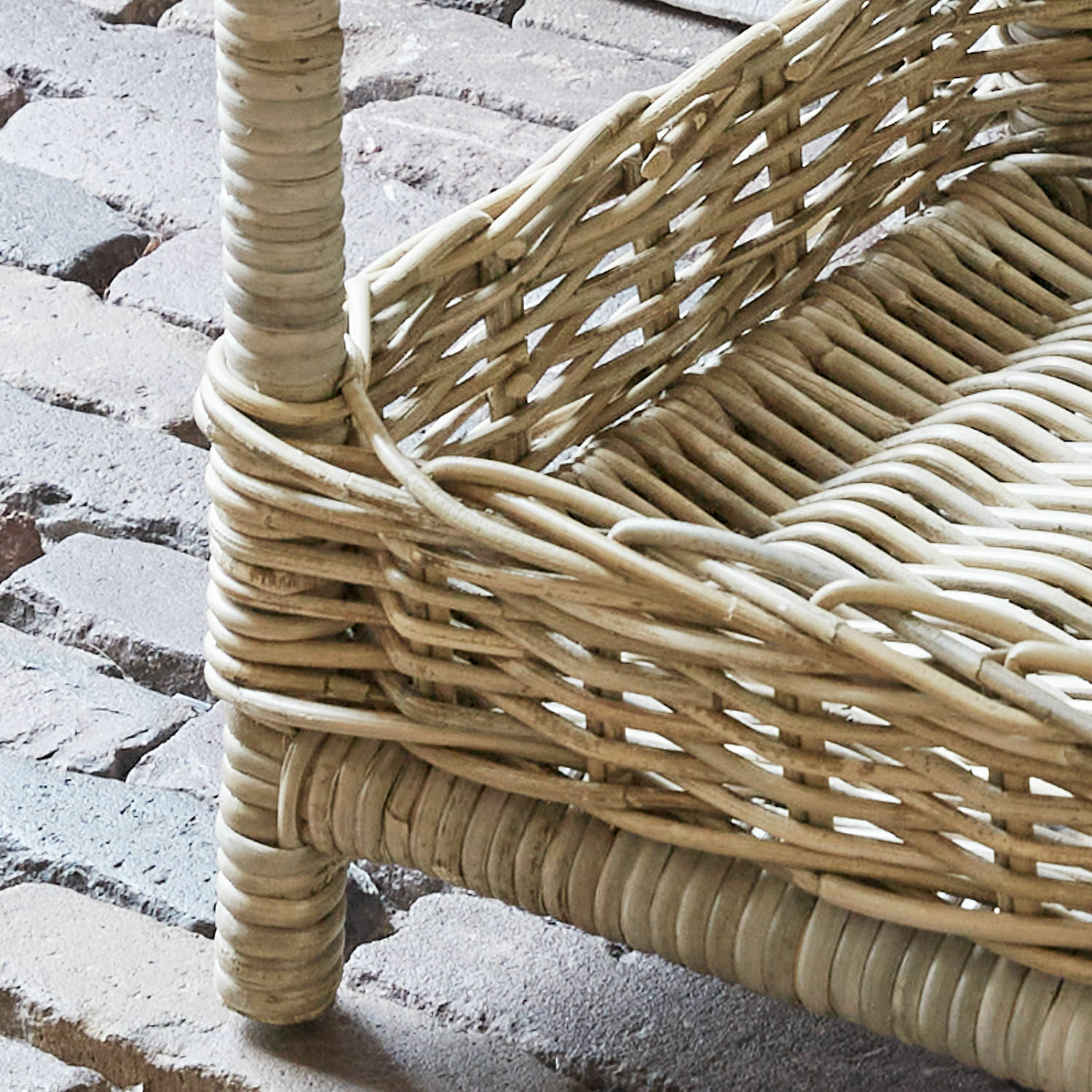 Korb aus natürlichem hellbraunem Rattan auf Steinboden, dekoratives Wohnaccessoire