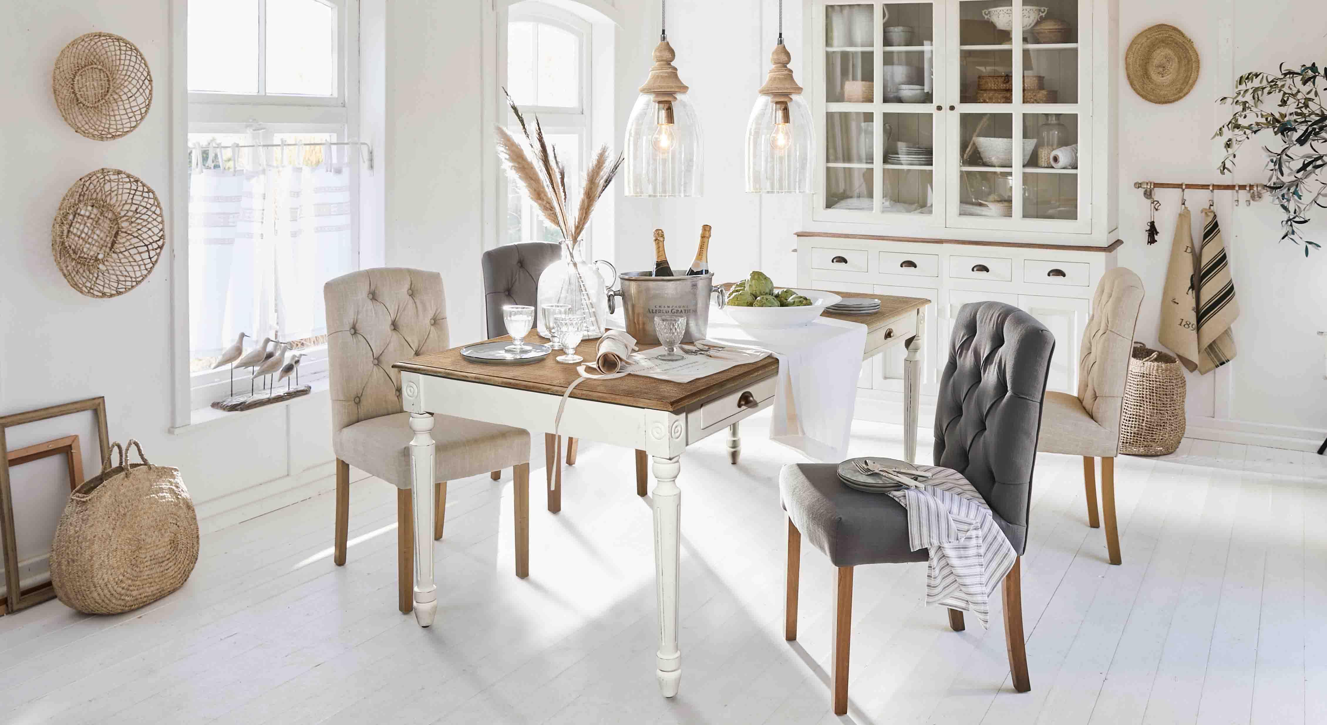 Rustikaler Essbereich mit weißem Holztisch und gepolsterten Stühlen in Beige und Grau in hellem Raum