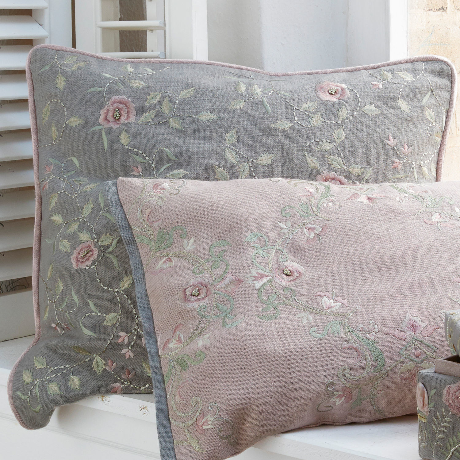 Wendbare Leinenkissen in Grau und Rosa mit zarten Blumenstickereien als Dekoration