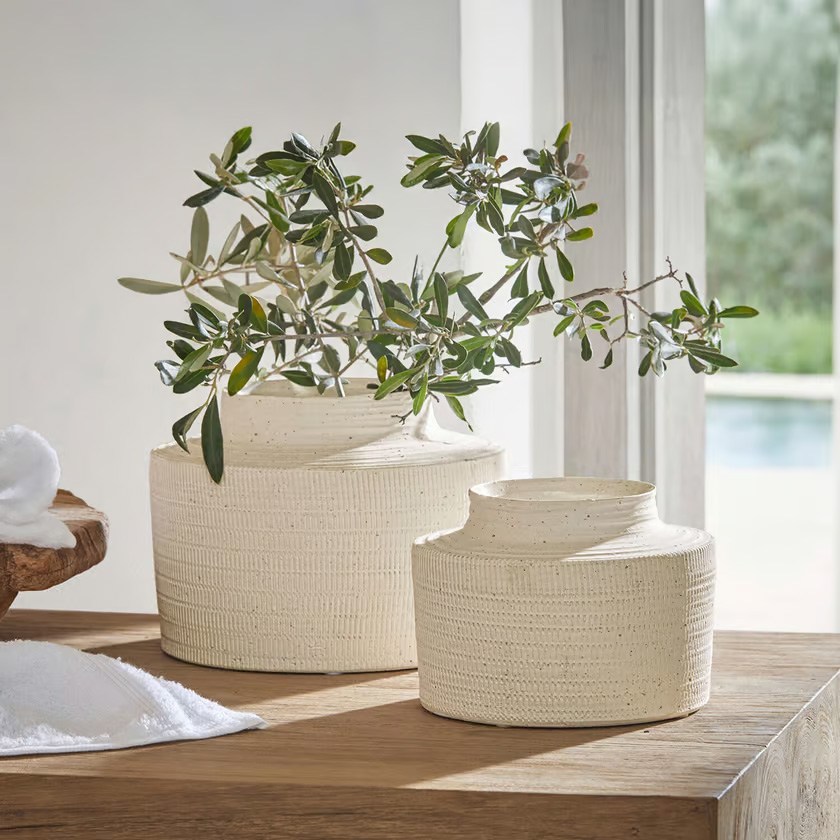 Zwei cremefarbene, strukturierte Keramikvasen auf Holztisch mit grünen Zweigen dekoriert