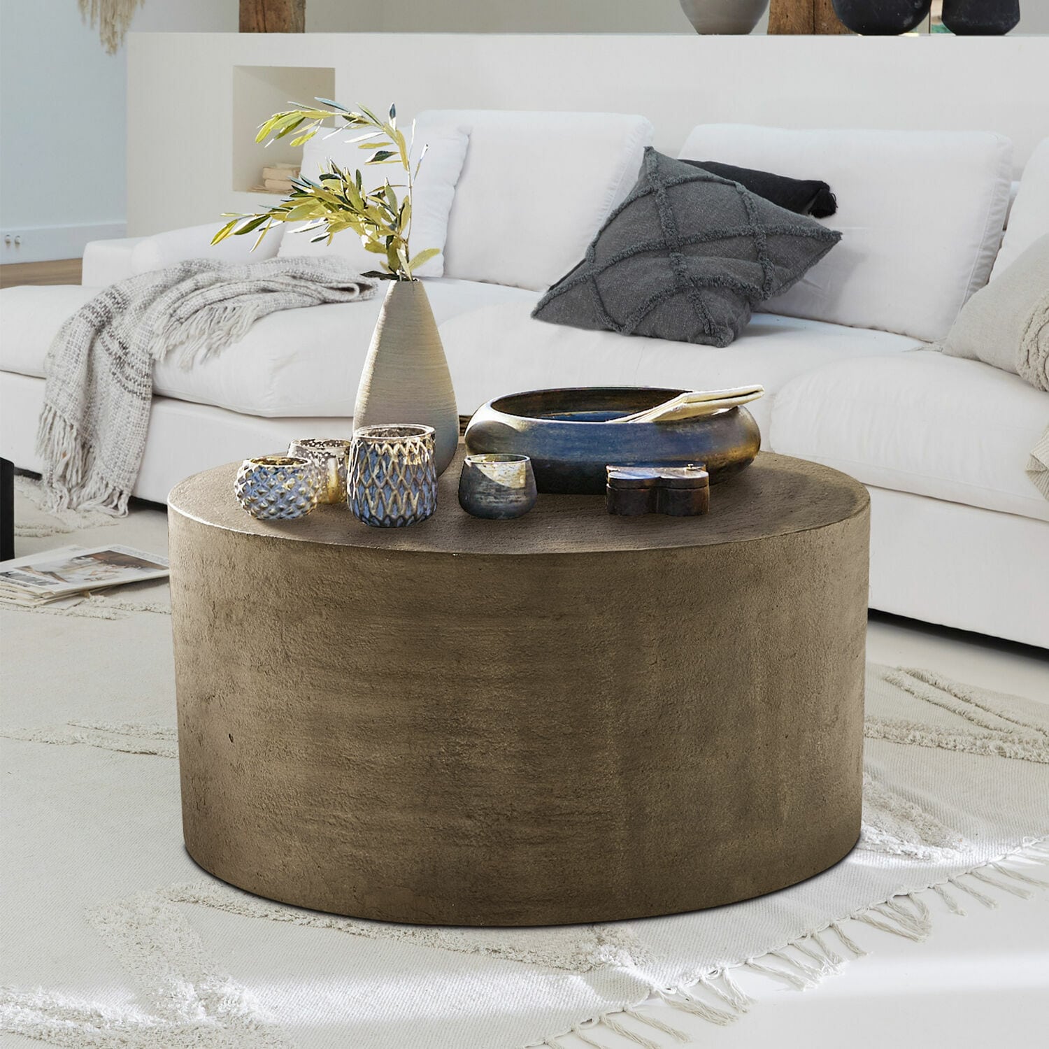 Runder Couchtisch aus braunem Beton auf hellem Teppich im modernen Wohnzimmer mit weißem Sofa