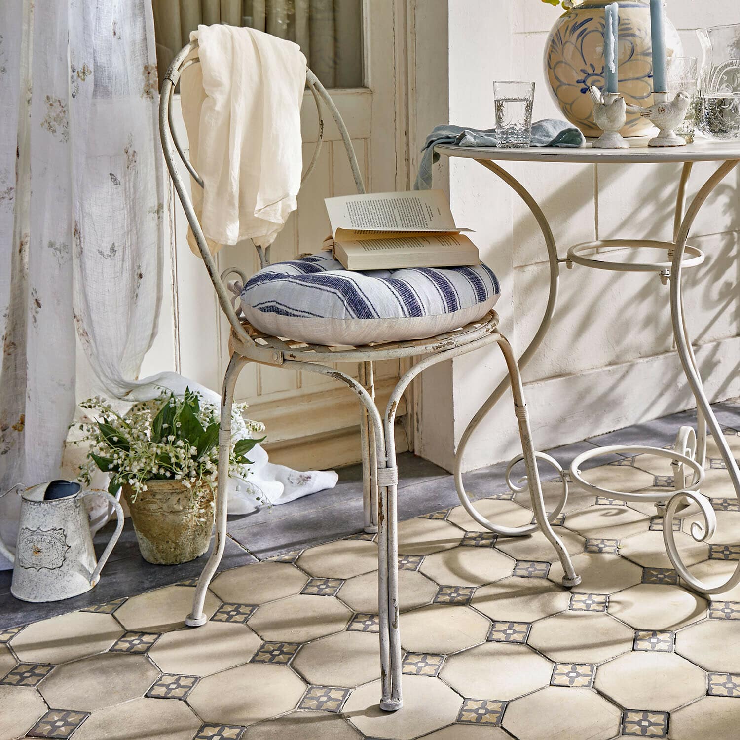 Stuhl Aube Vintage Metallstuhl mit blau-weiß gestreiftem Kissen und weißem Tuch im hellen Raum mit Fliesenboden