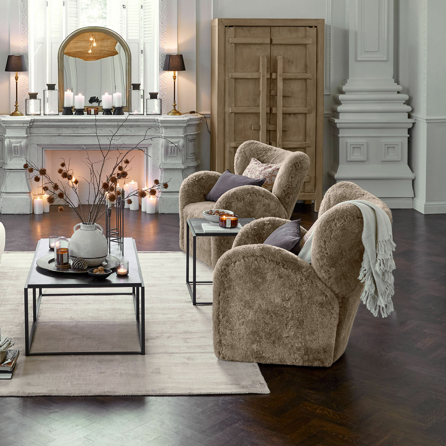 Bequeme Sessel aus beigem Plüsch in elegantem Wohnzimmer mit Kamin und Holzschrank