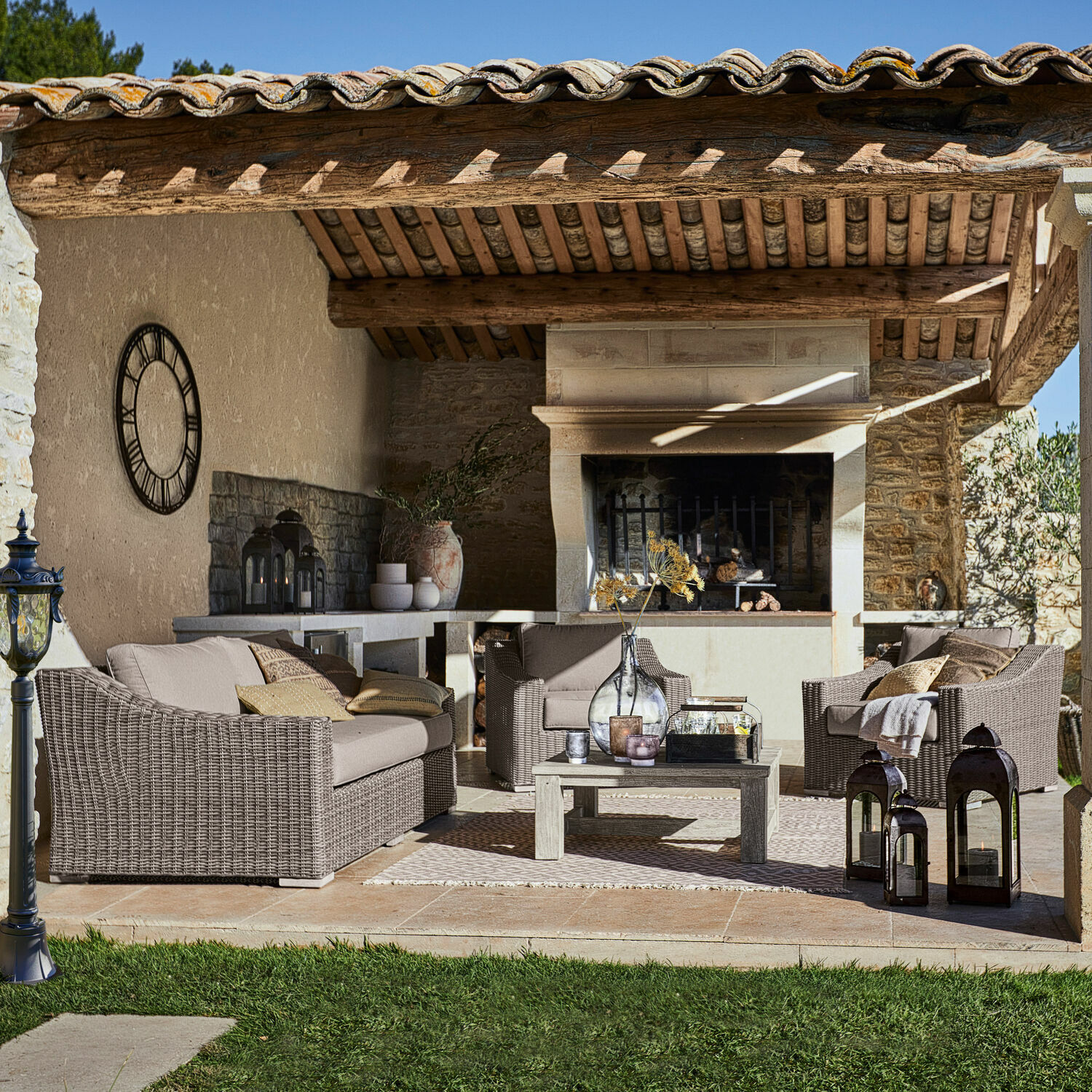 Gartenmöbel-Set aus braunem Rattan mit beigen Polstern auf Terrasse mit Kamin