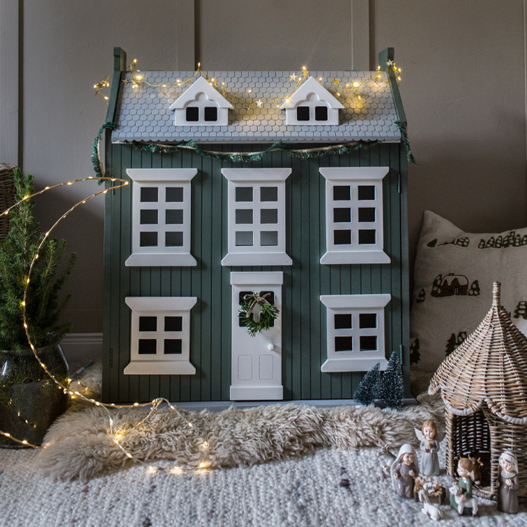 Grünes Holzhaus mit weißen Fenstern und Lichterkette, weihnachtliche Wohnraumdekoration