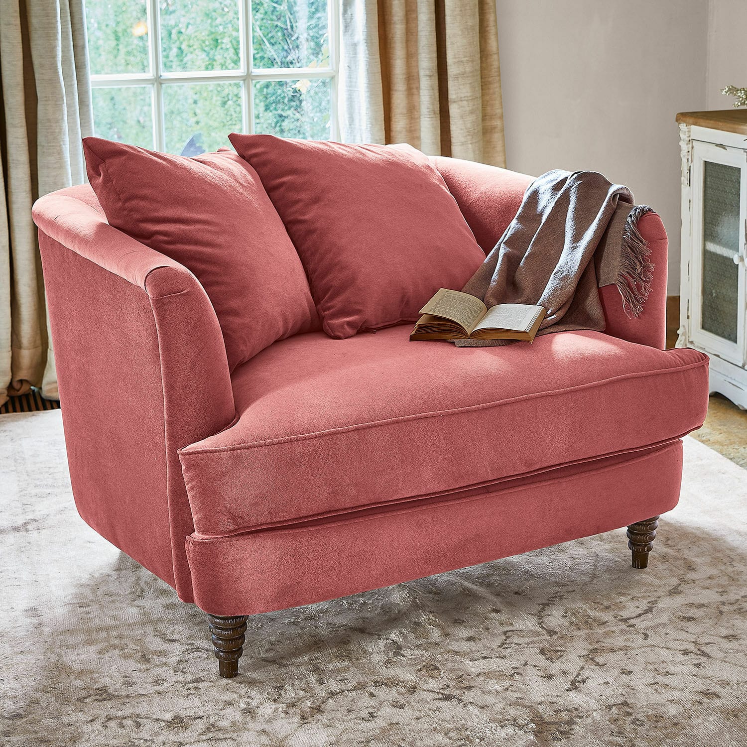 Sessel Etueffont Rosa Sofa aus weichem Stoff mit Kissen und grauem Plaid auf hellem Teppich im Wohnzimmer