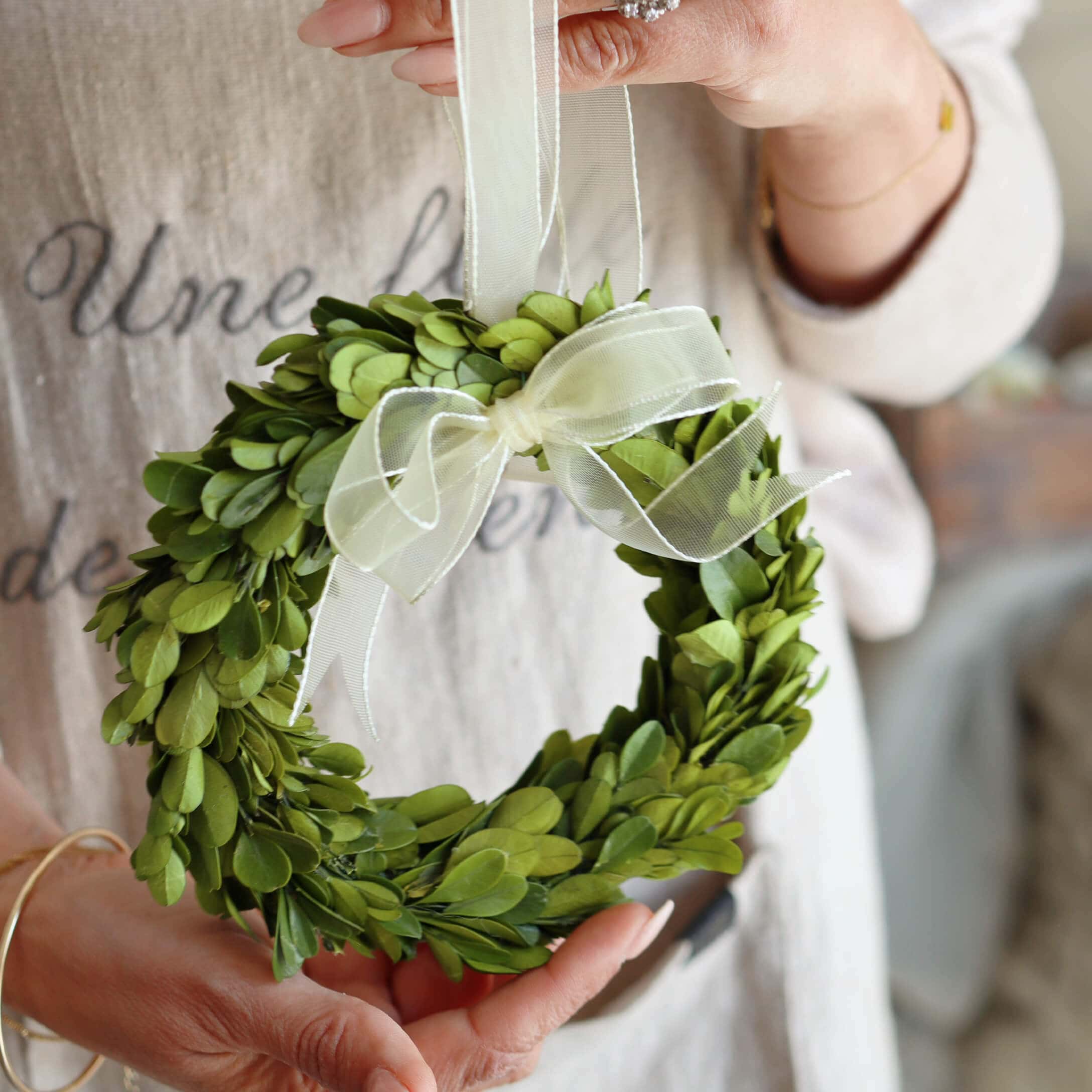Kleiner grüner Kranz aus Blättern mit weißer Schleife, Dekoration für Zuhause oder Tür