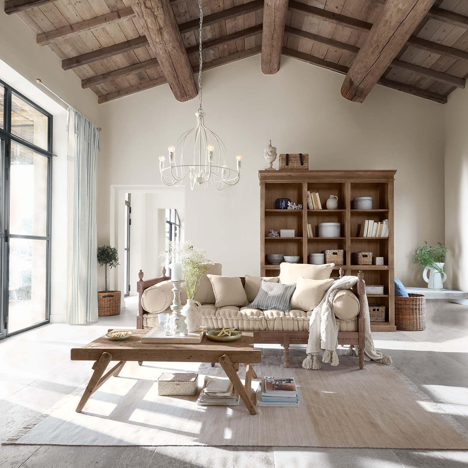 Gemütliches Wohnzimmer mit Holztisch und beigem Sofa unter sichtbarem Holzbalkendach