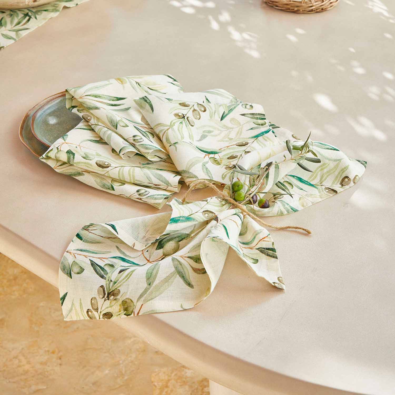 Leinenservietten in Creme mit grünem Olivenmuster auf Tisch, stilvolle Tischdekoration