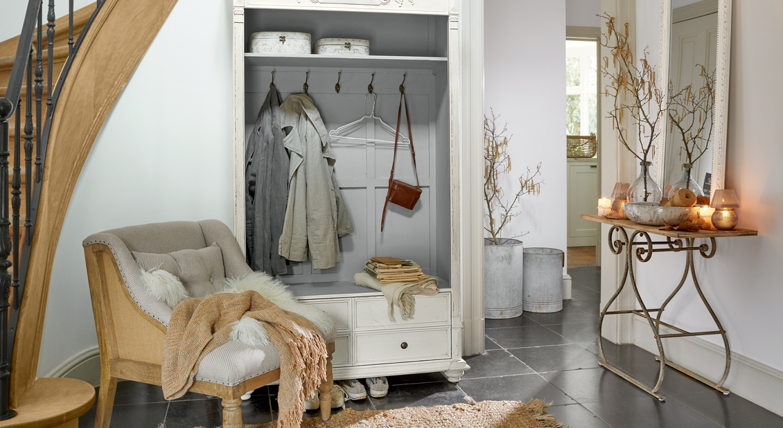 Gemütlicher Eingangsbereich mit weißem Holzschrank und beigem Vintage-Sessel auf dunklem Boden