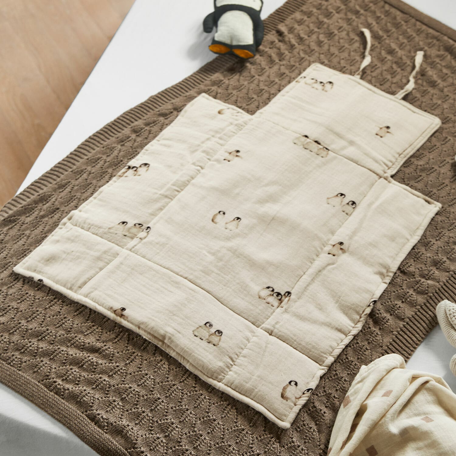 Wickelunterlage Jocienne Beige Baumwoll-Kinderkrabbeldecke mit Pinguin-Motiv auf braunem Strickdecke, Babyzubehör