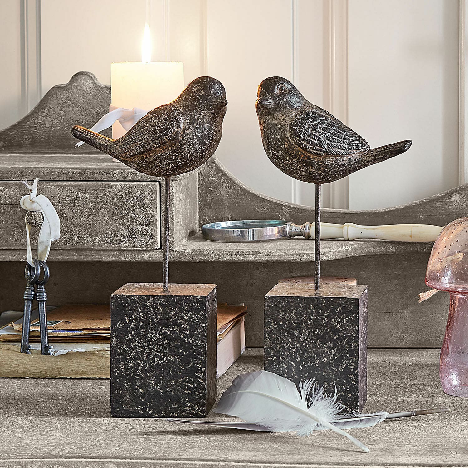 Deko-Vogel 2er Set Juxivel Dekorative Vögel aus dunklem Metall auf quadratischen Ständern auf rustikalem Tisch mit Feder