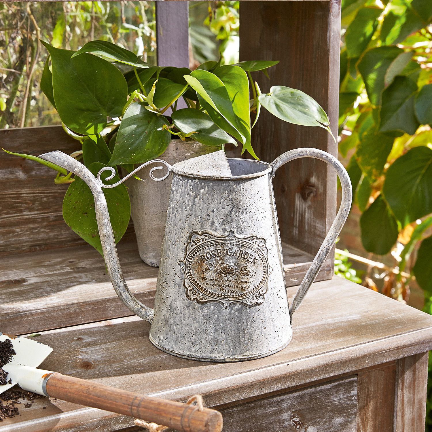 Gießkanne Rose Garden Vintage Metall-Gießkanne mit Rose Garden Schriftzug auf Holztisch im Garten