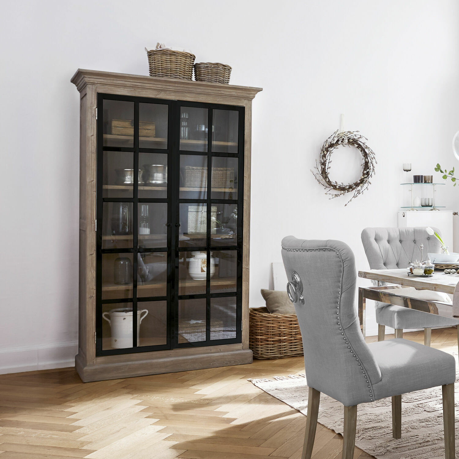 Holzvitrine mit schwarzen Glastüren in hellem Wohnzimmer mit Essbereich