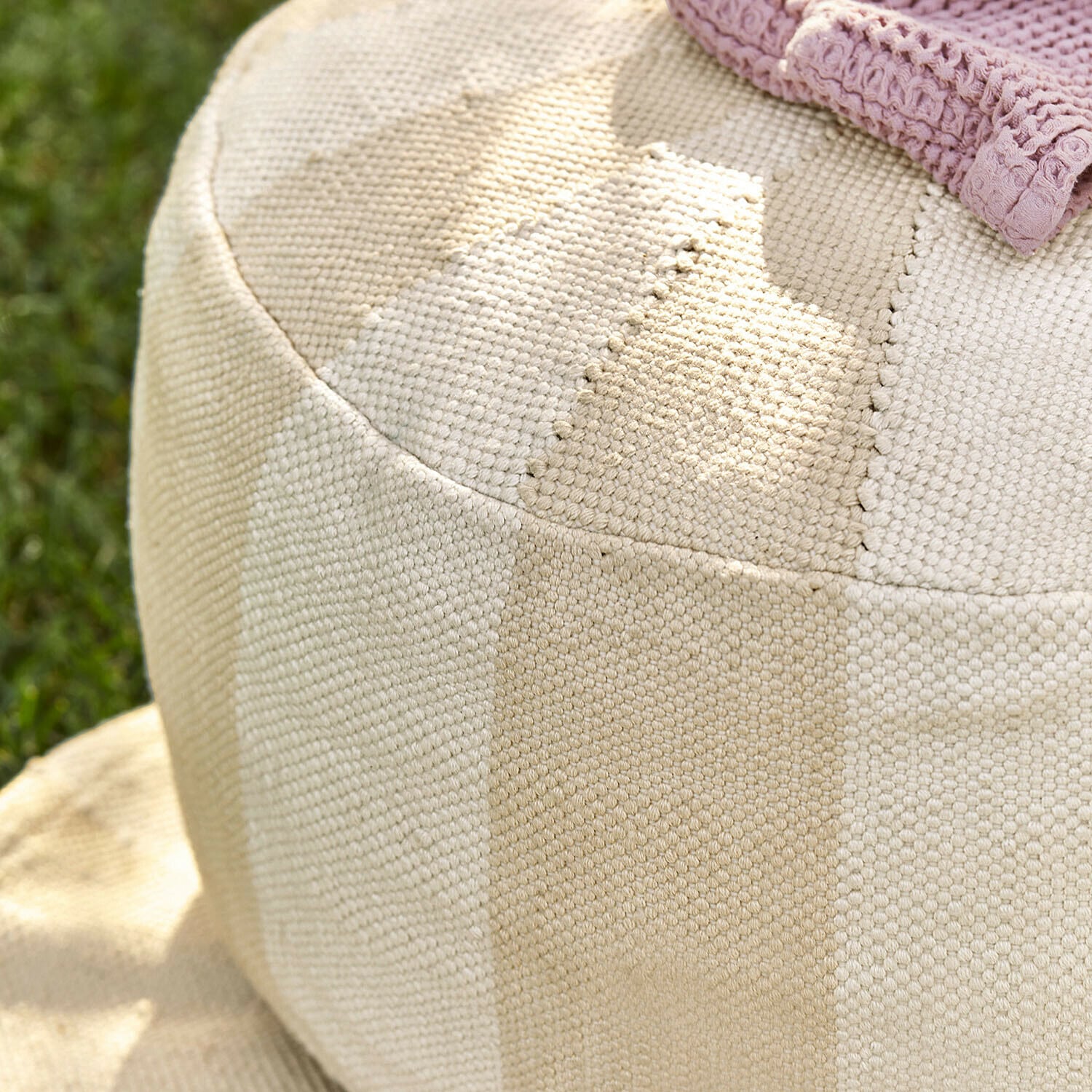 Beiger Baumwoll-Pouf mit gestreifter Struktur, ideal zum Entspannen im Garten