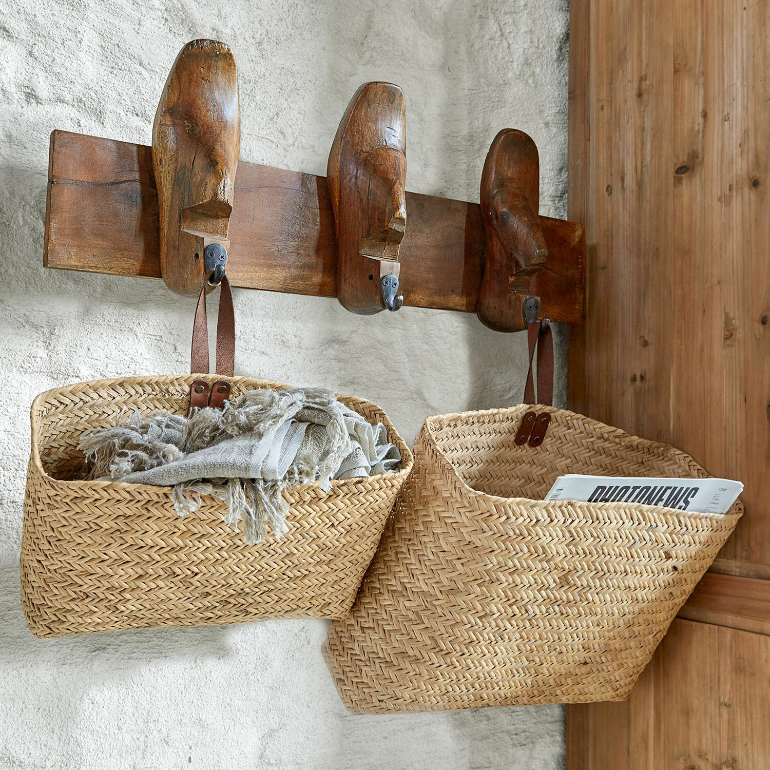 Zwei hängende Körbe aus geflochtenem Rattan in Naturfarbe mit Ledergriffen zur Aufbewahrung im Haus