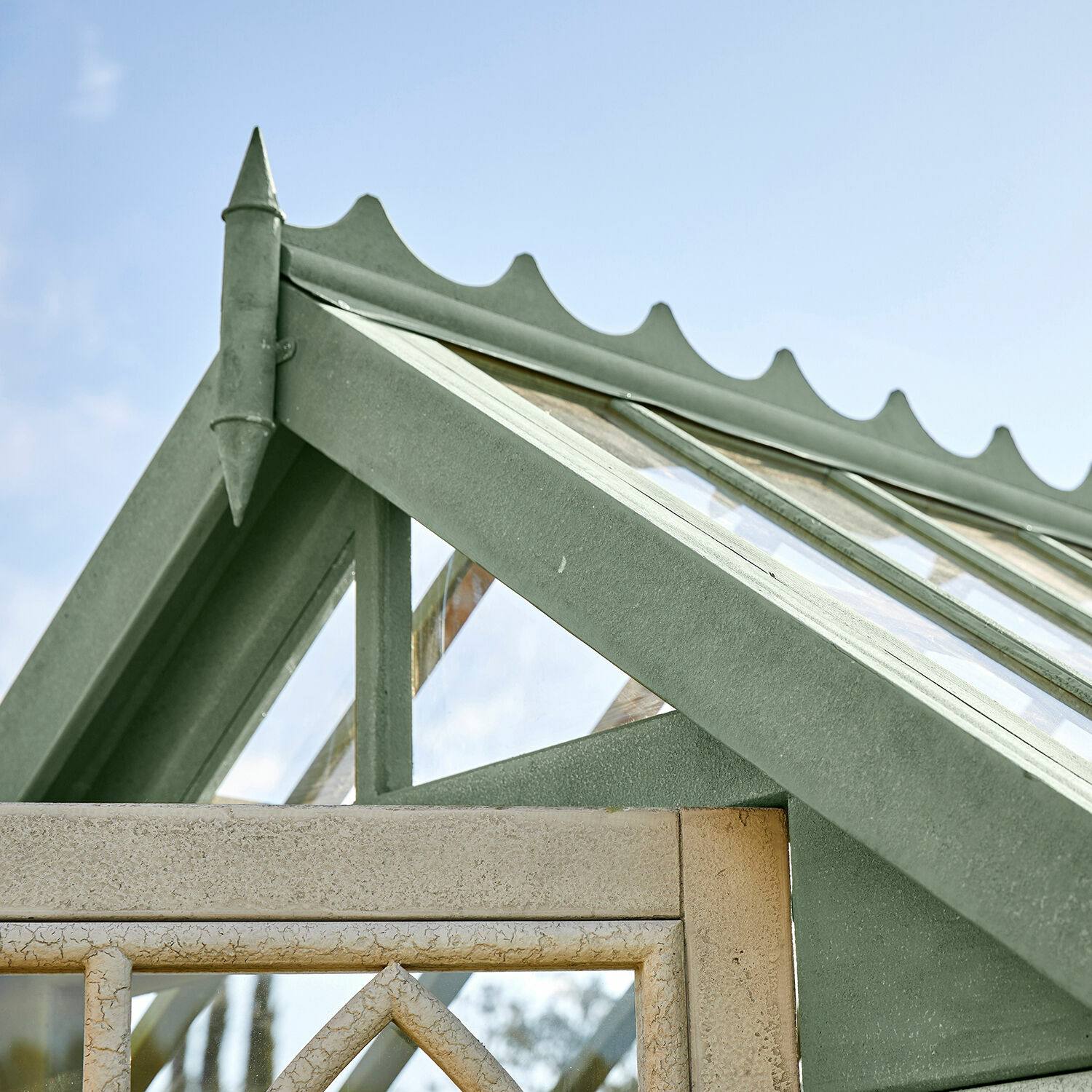 Grünes Metall-Dach einer Gewächshaus mit dekorativem Giebel und Glasfenstern für Garten
