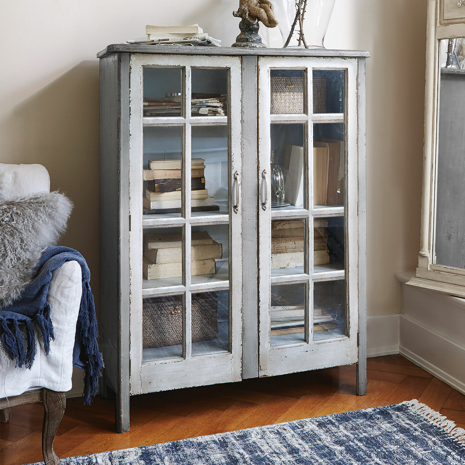 Kommode Sherman Grauer Holzvitrinenschrank mit Glastüren und antikem Vintage-Finish im Wohnraum