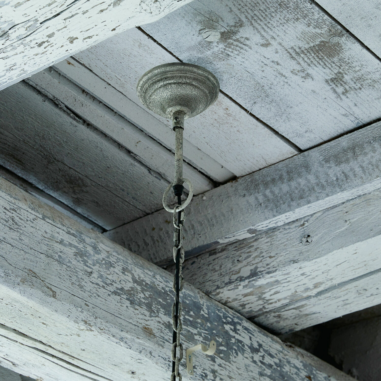 Metallkette mit antik weißer Patina an Decke aus verwitterten Holzbalken