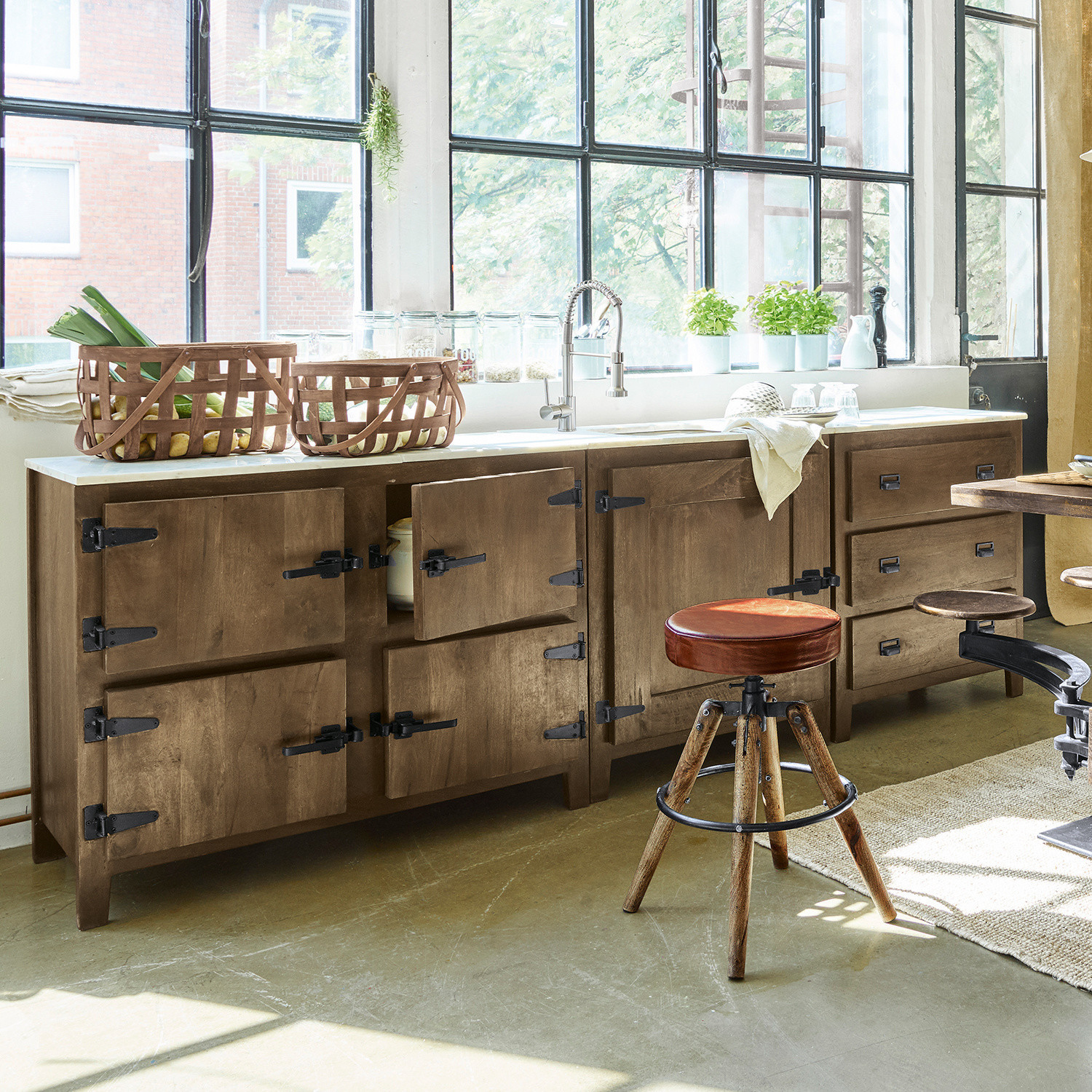 Küche mit braunem Holzschrank und weißer Arbeitsplatte, Industrie-Fenster und Hocker mit rotem Sitz