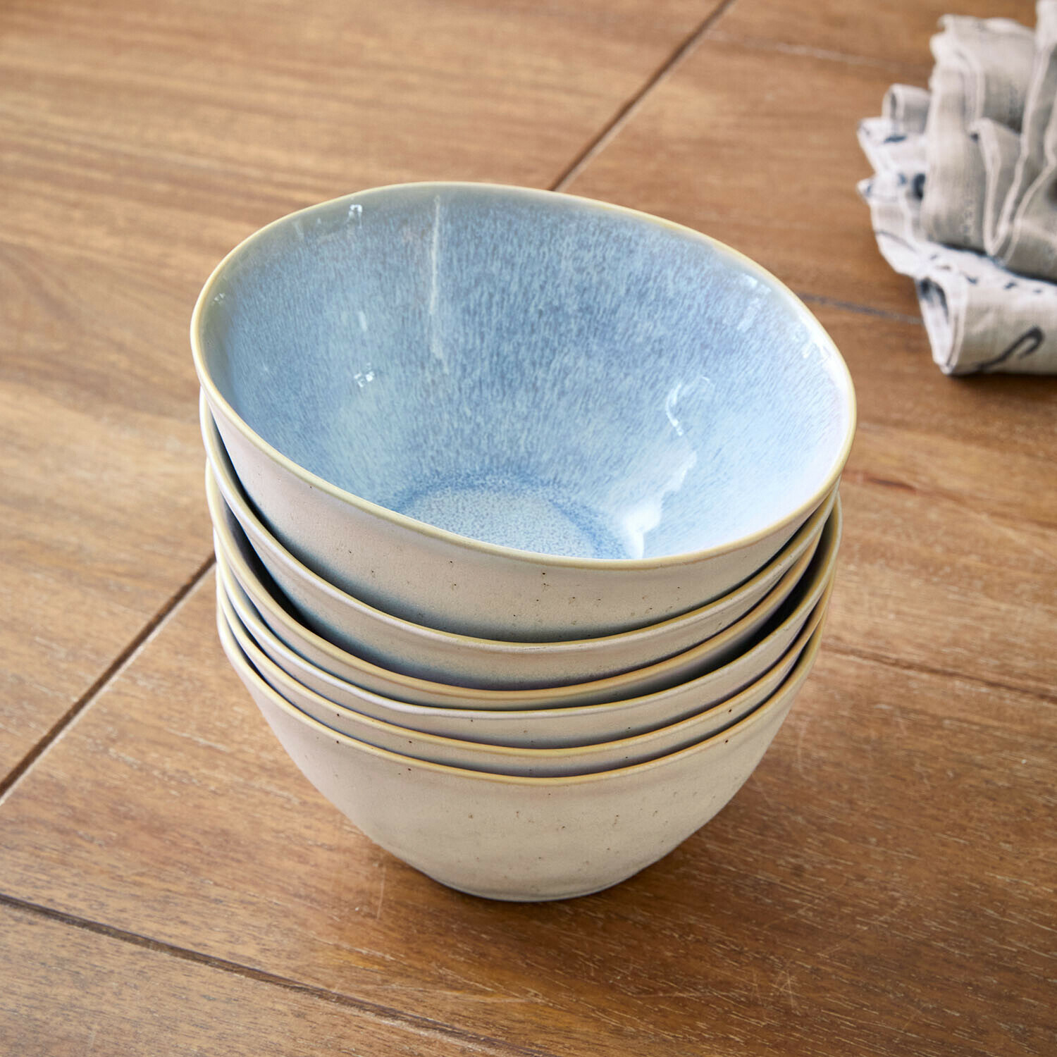 Sechser-Set cremefarbener Keramikschalen mit blauem Innenraum auf Holztisch