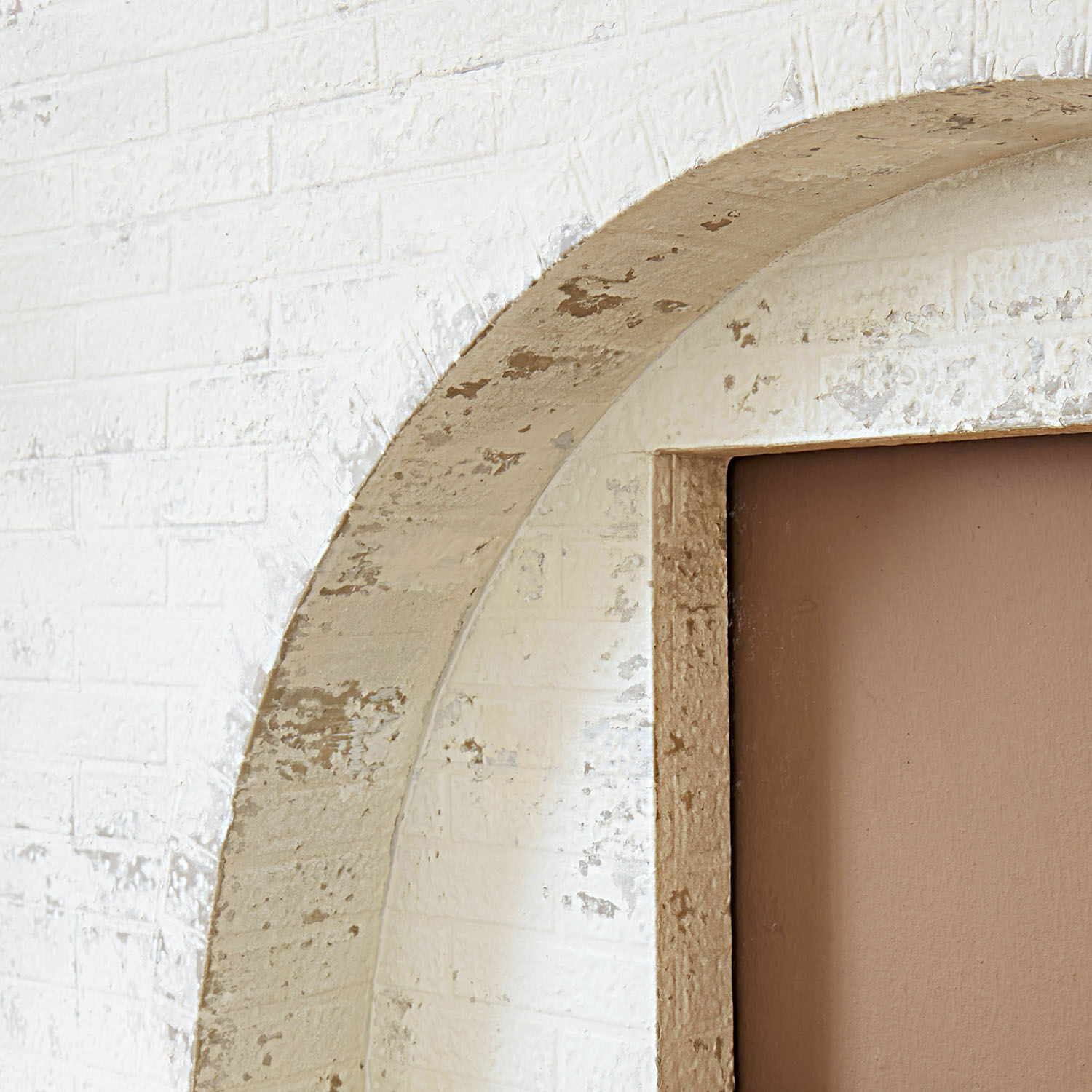 Detail eines weißen Ziegelbogens mit gealtertem beigem Rahmen und brauner Tür im Vintage-Stil