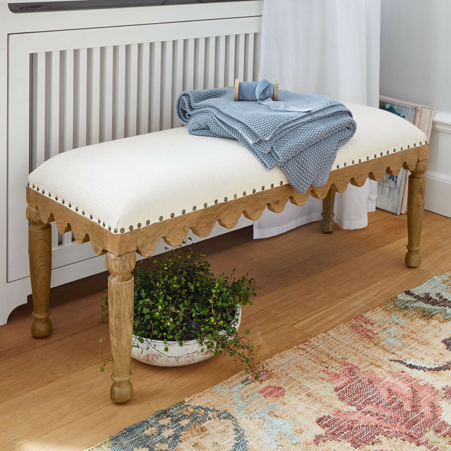 Bank Marais Légère Bank aus hellem Holz mit cremefarbenem Polster und blauer Strickdecke in gemütlichem Zimmer