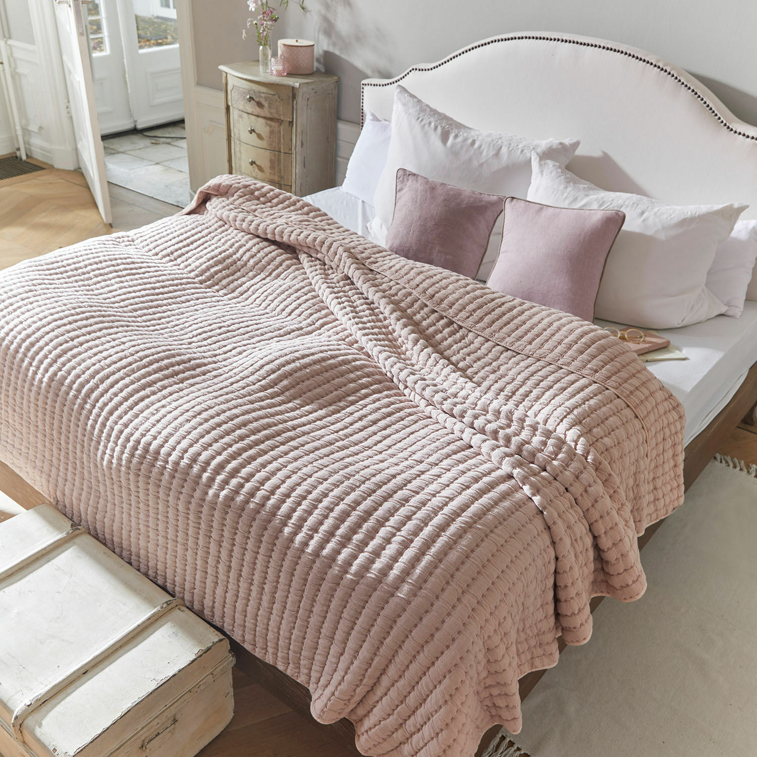 Rosa gesteppte Decke aus weichem Material auf Bett mit weißer Bettwäsche und Kissen