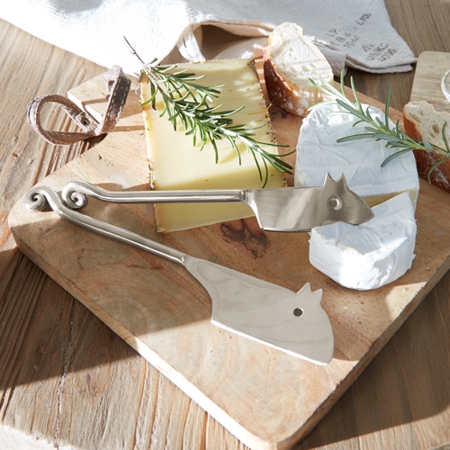 Set aus Edelstahl-Käsemessern auf Holzbrett mit Käse und Kräutern, Küchenzubehör