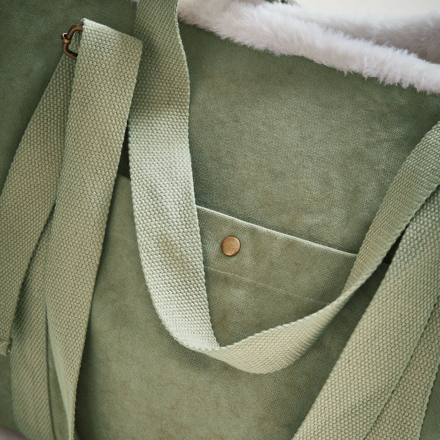 Grüne Stofftasche mit weichem weißem Fellfutter und breiten Tragegurten aus Textil