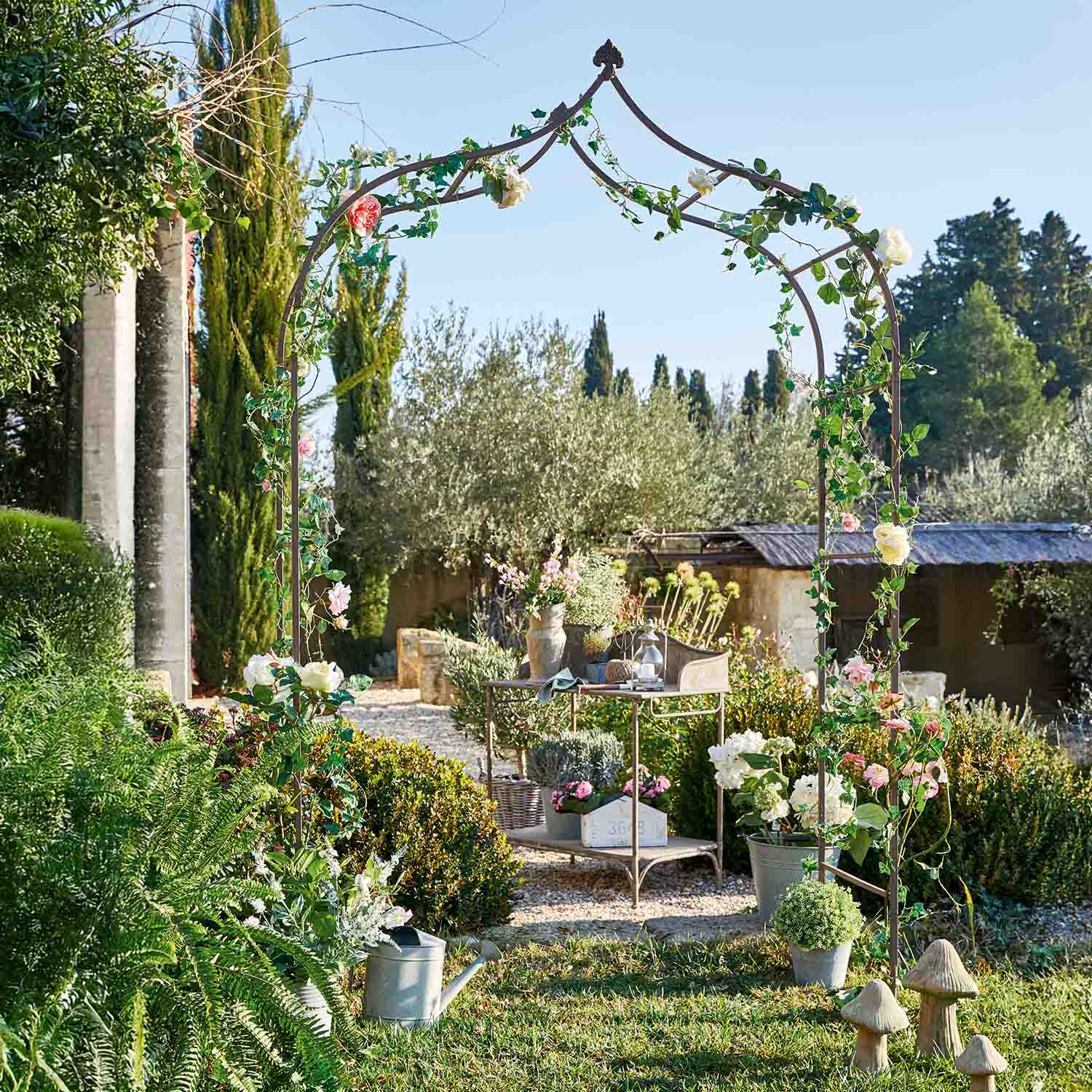 Metall-Gartenpergola mit grünem Laub und rosa Blüten in sonnigem Garten