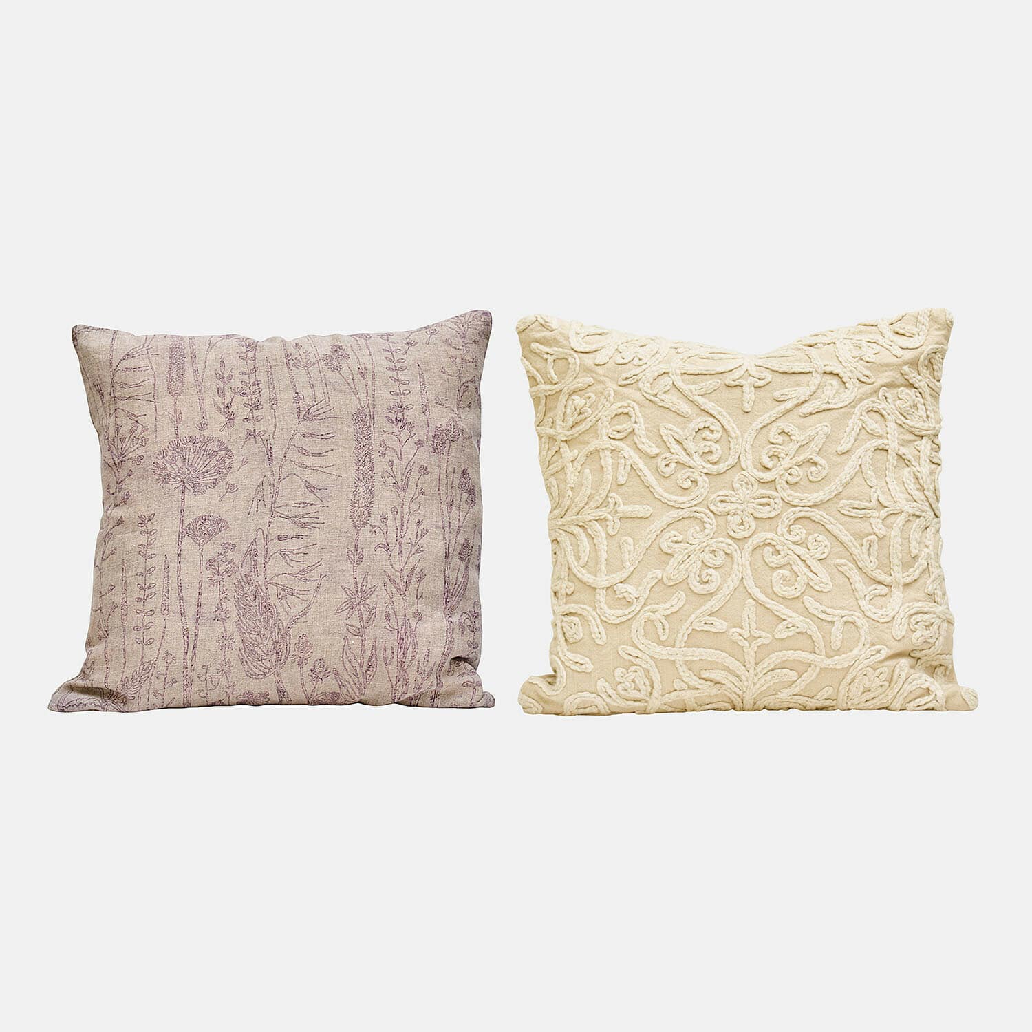 Zwei dekorative Kissen, eines beige mit lila Pflanzenmuster, das andere cremefarben mit Stickerei
