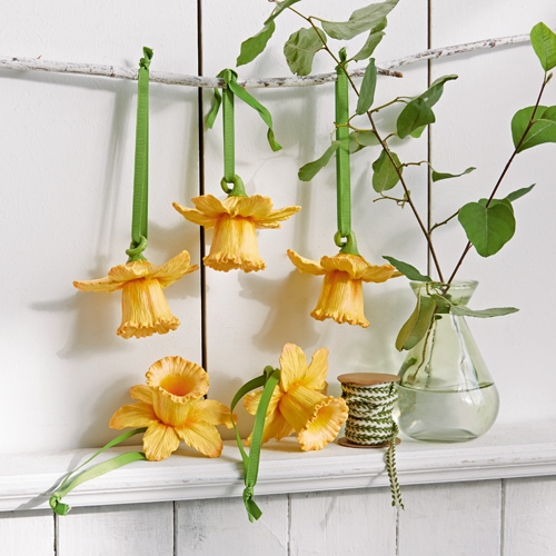 Gelbe Stoffblumen mit grünen Bändern zum Aufhängen, natürliche Dekoration im Landhausstil.