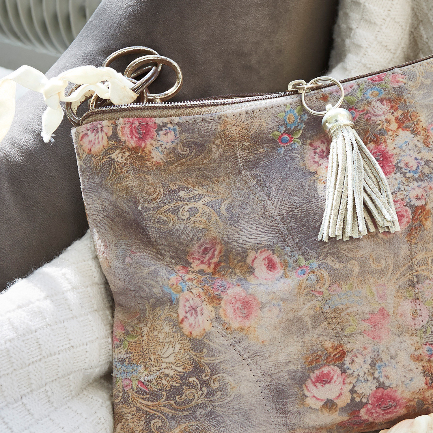 Wildledertasche mit floralem Muster, Quaste und Metallring in sanften Pastellfarben